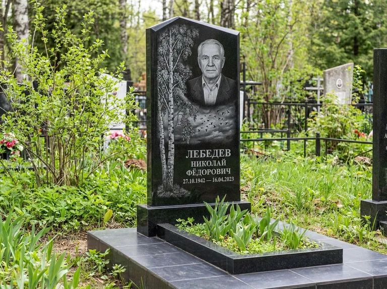 Памятник с гравировкой берёзы: вертикальная стела со скошенным верхом — берёза и стая птиц в небе, гранитный цоколь с тёмной плиткой, работа «Лебедев» в Волгограде
