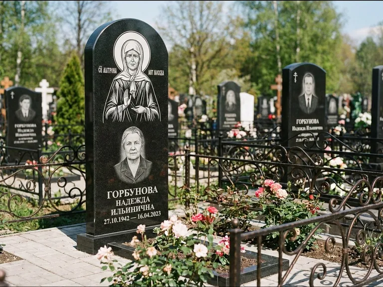 Памятник с гравировкой иконы: стела с арочным верхом и киотом под образ — гравировка образа Матроны Московской, гранитный цоколь с тёмной плиткой, работа «Ковалёв» в Волгограде