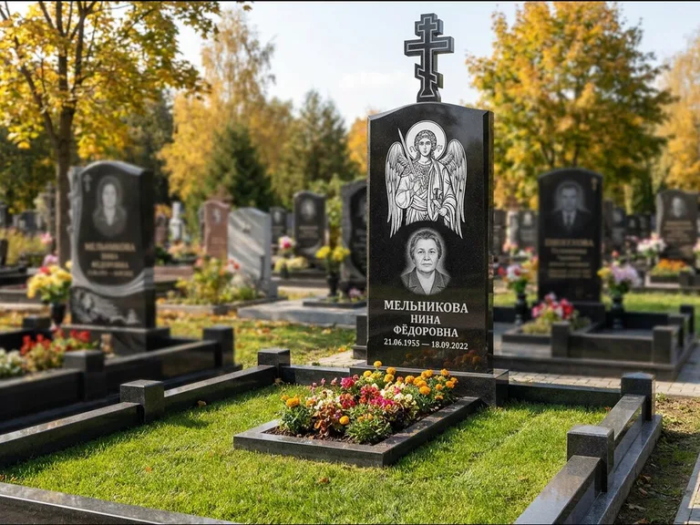Памятник с гравировкой иконы: округлая стела-медальон с ликом — гравировка Богородицы «Семистрельная», луговые травы и полевые цветы за участком, работа «Гущин» в Волгограде