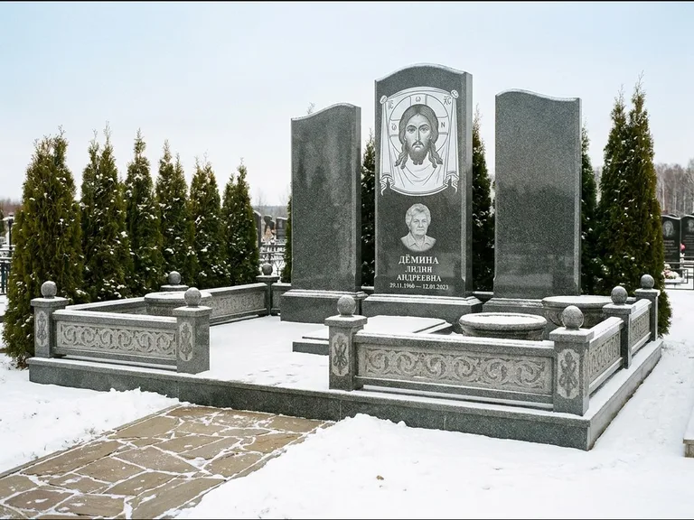 Памятник с гравировкой иконы: узкая вертикальная стела-пилон с ликом — икона в резной рамке-киоте, открытая лужайка без ограды, работа «Одинцов» в Волгограде