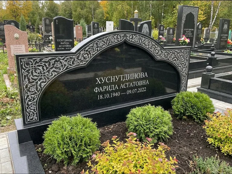 Мусульманский памятник: вытянутая горизонтальная семейная стела с аркой — белая гравировка силуэта мечети с минаретами, участок с декоративными кустами, работа «Зарипова» в Волгограде
