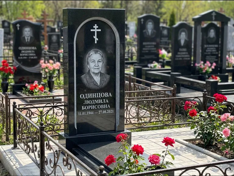 Памятник из чёрного гранита — скромная невысокая стела с крестом с терновым венцом, работа «Лаврентьева» в Волгограде