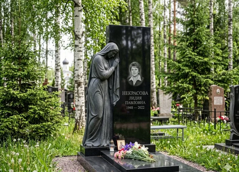 Гранитная фигура скорбящего мужчины у чёрной стелы в Волгограде
