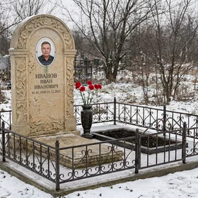 Памятник из известняка арочной формы с цветами